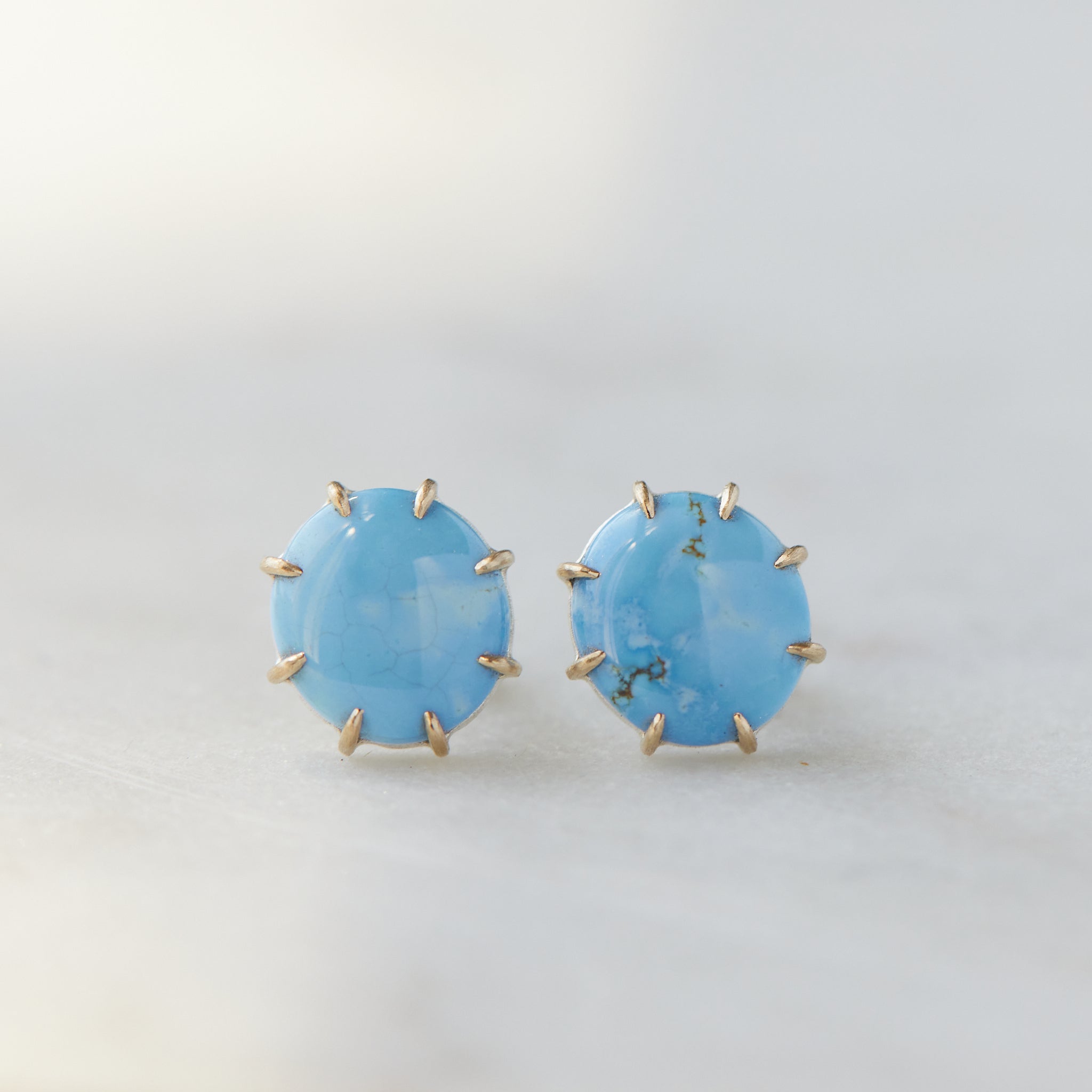 oval lavender turquoise cabochons are set in gold prongs in these stud earrings.