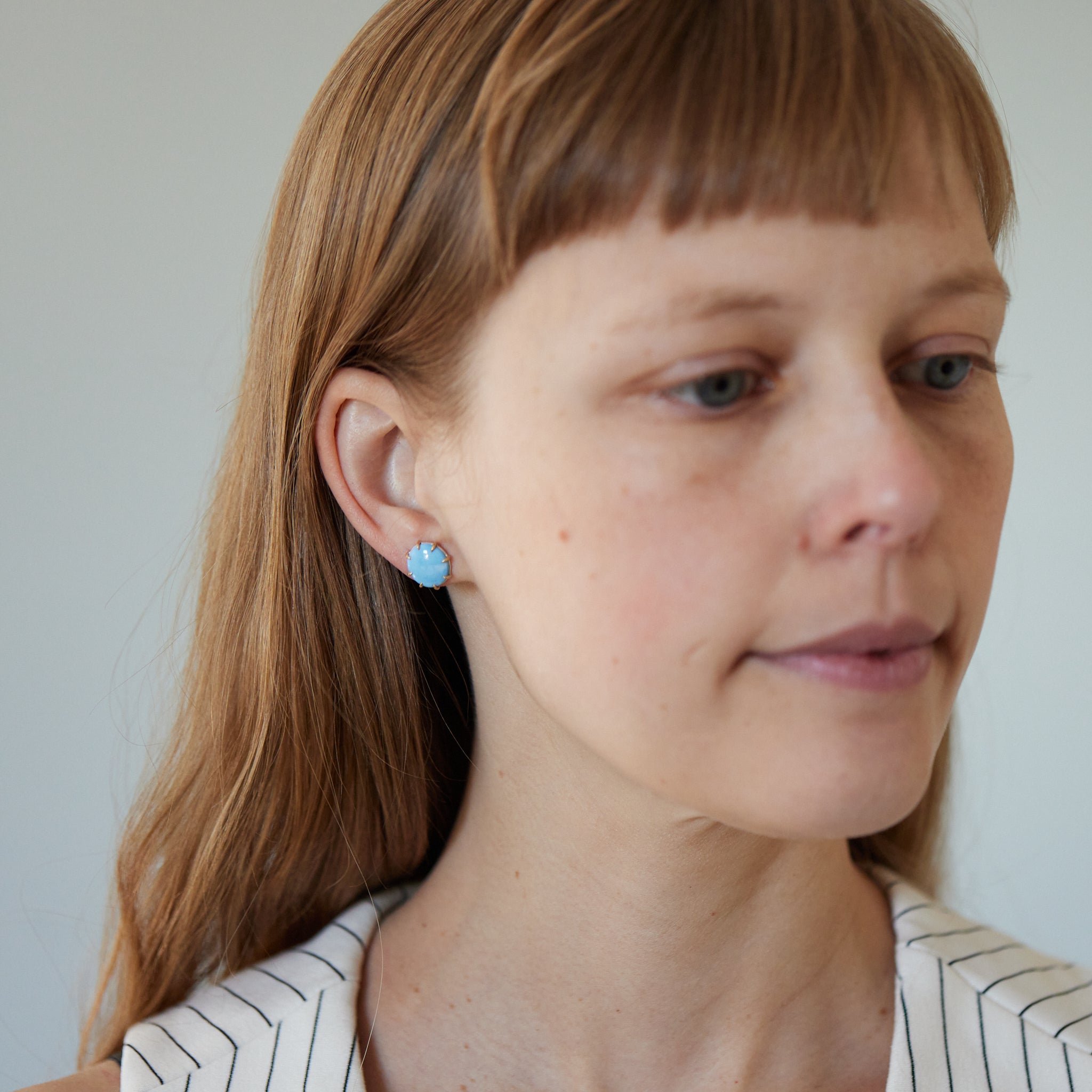 oval lavender turquoise cabochons are set in gold prongs in these stud earrings. Photographed on person.