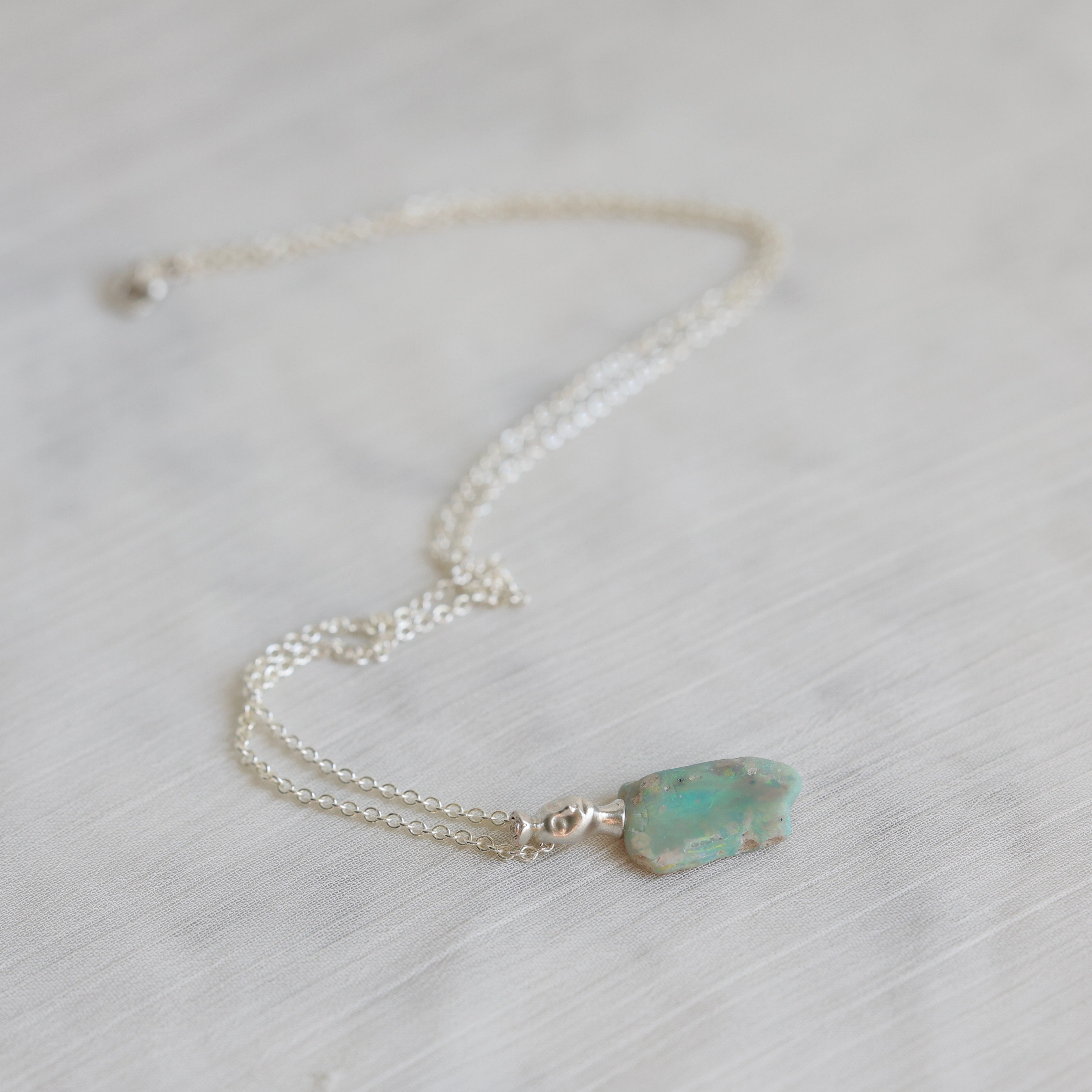 Necklace with a green opal pendant on a light background