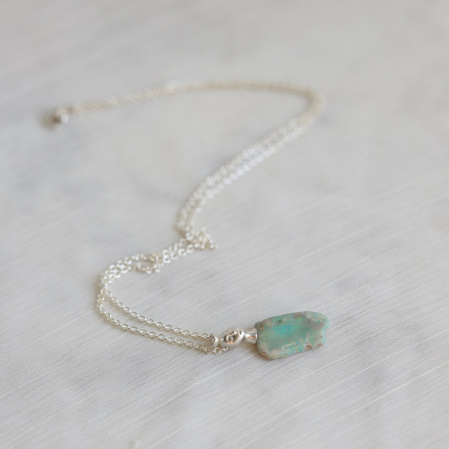 Necklace with a green opal pendant on a light background