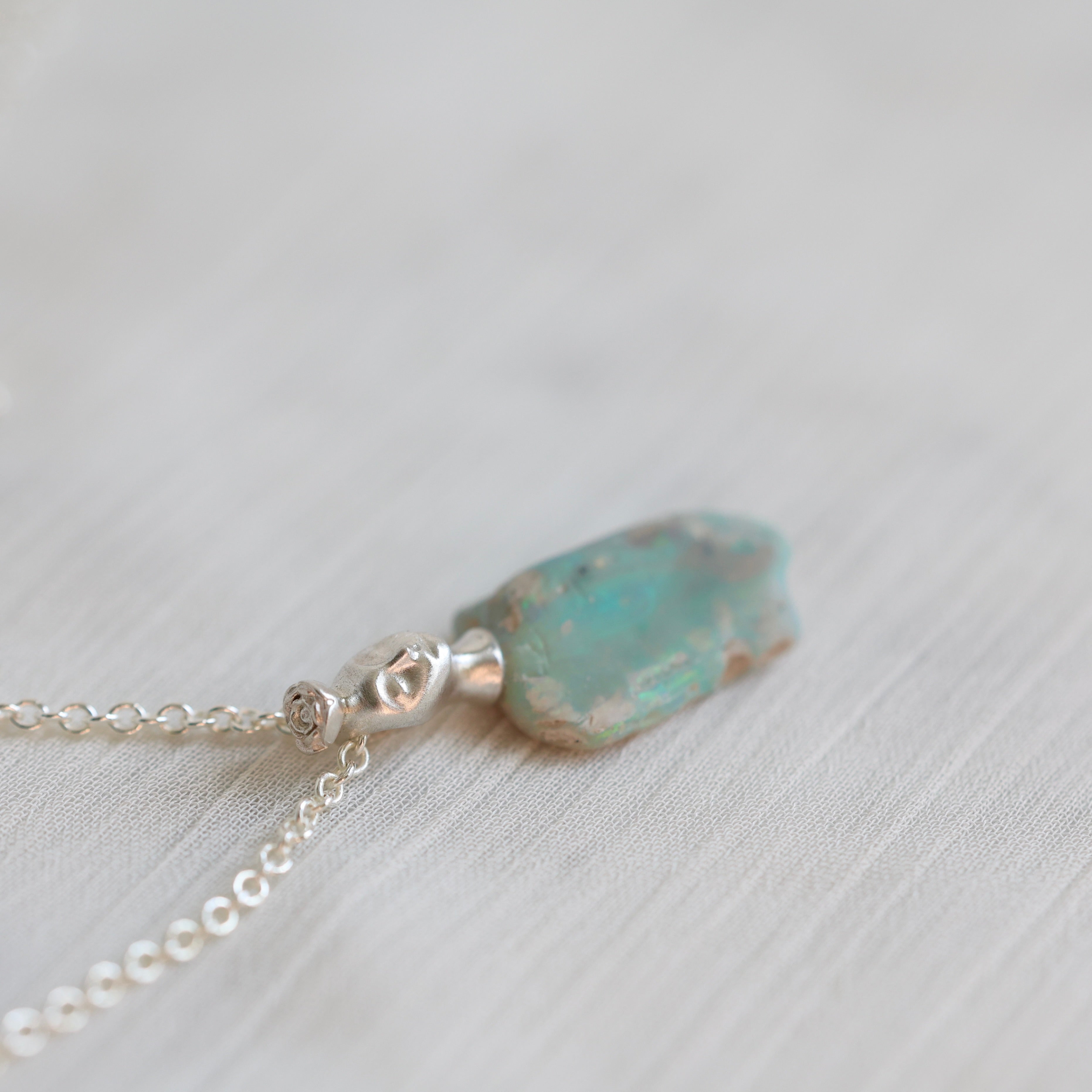 Necklace with a green opal pendant on a light background