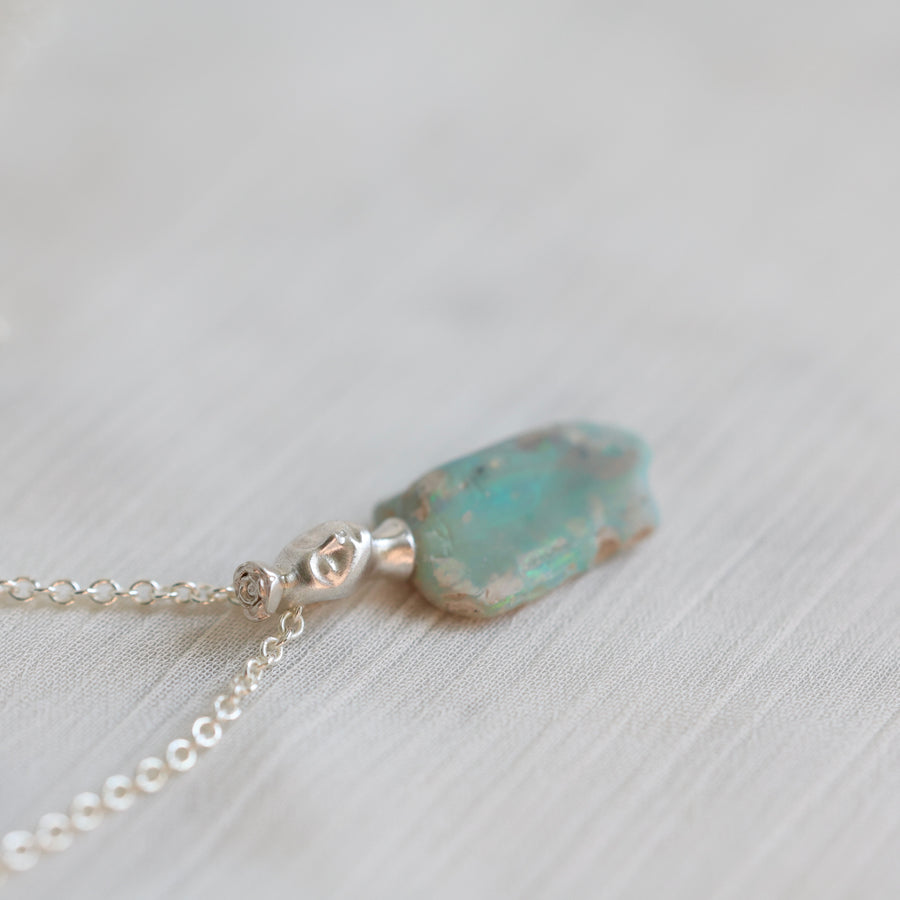 Necklace with a green opal pendant on a light background