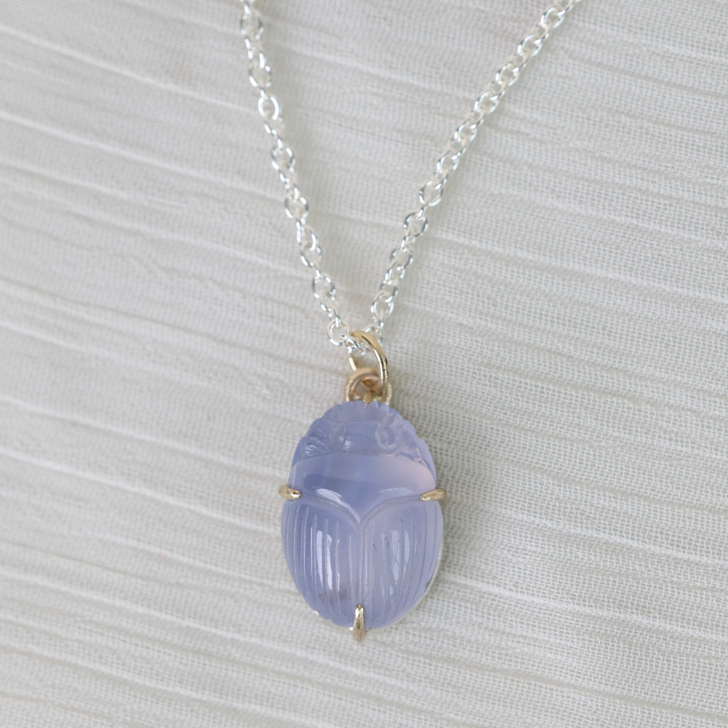 Necklace with a purple scarab pendant on a light gray background