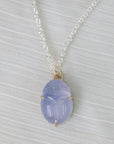 Necklace with a purple scarab pendant on a light gray background