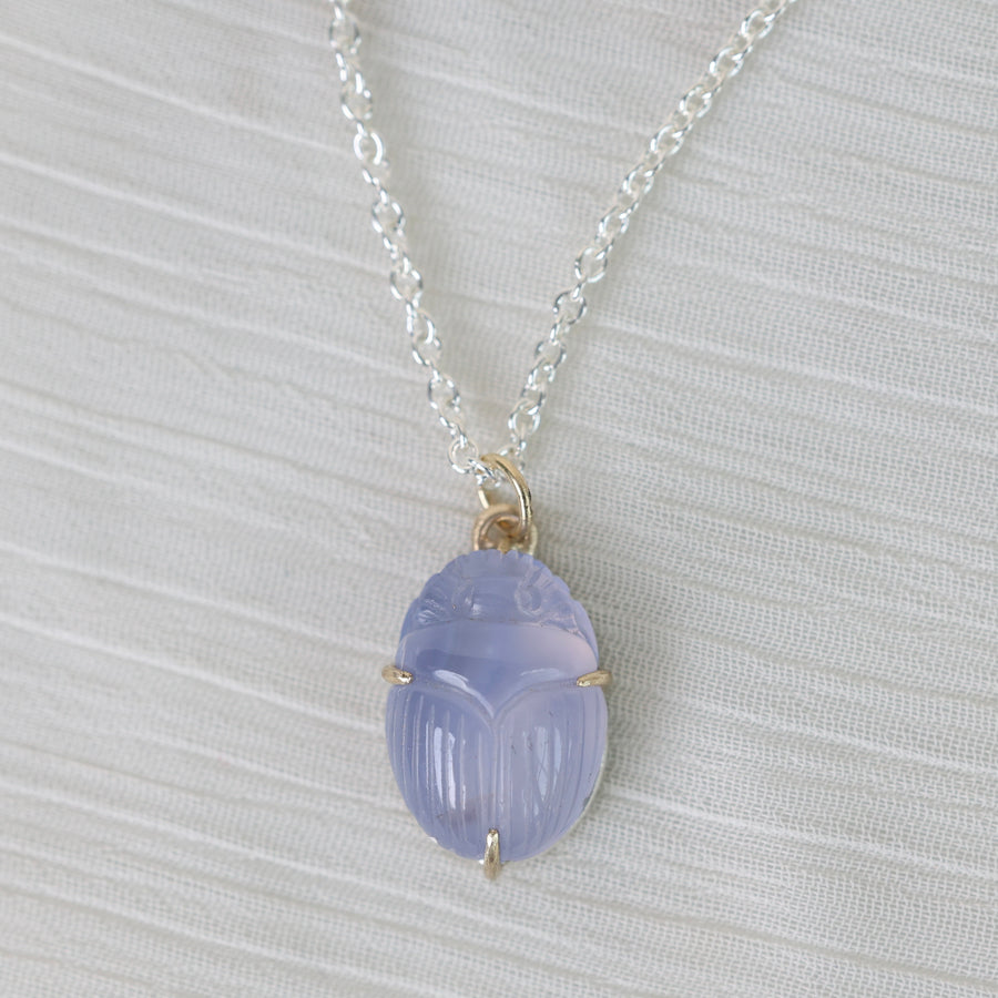 Necklace with a purple scarab pendant on a light gray background