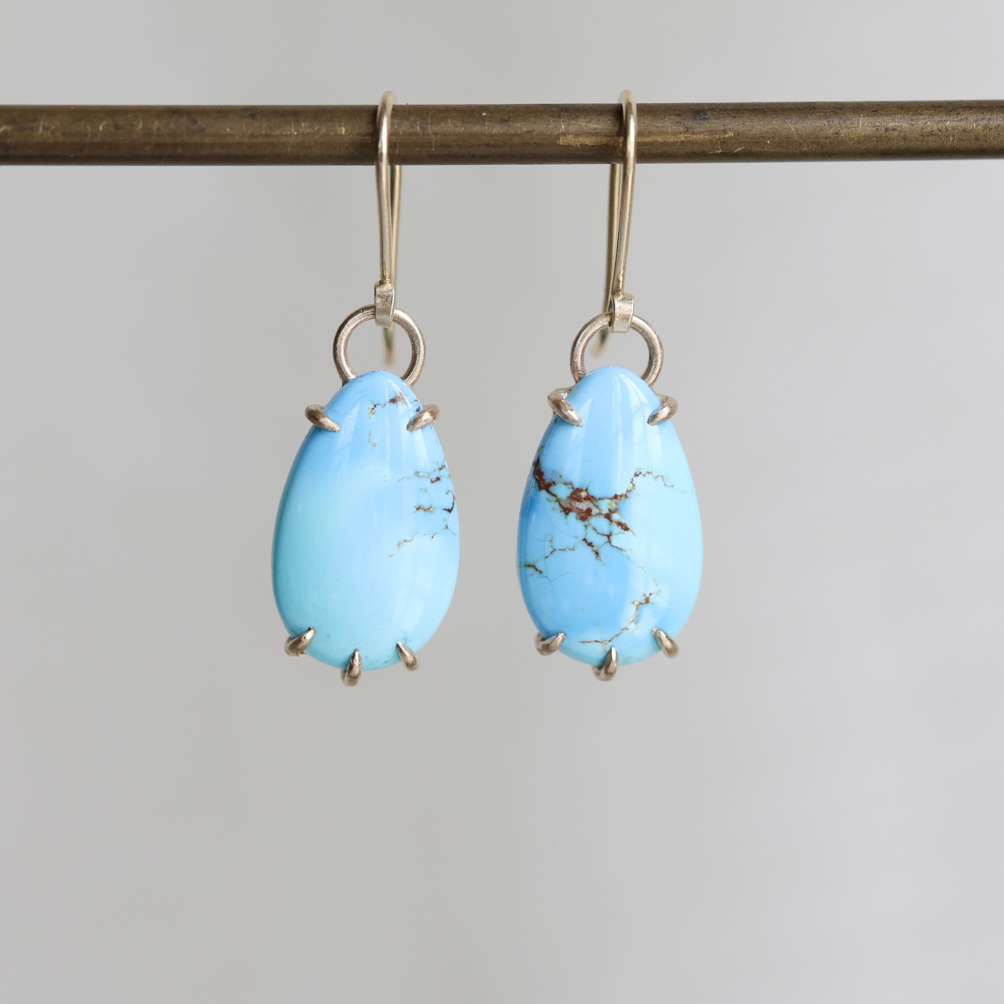 Pair of blue teardrop earrings on a gray background