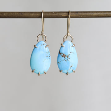 Pair of blue teardrop earrings on a gray background