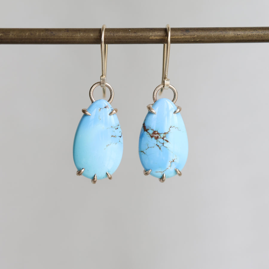 Pair of blue teardrop earrings on a gray background