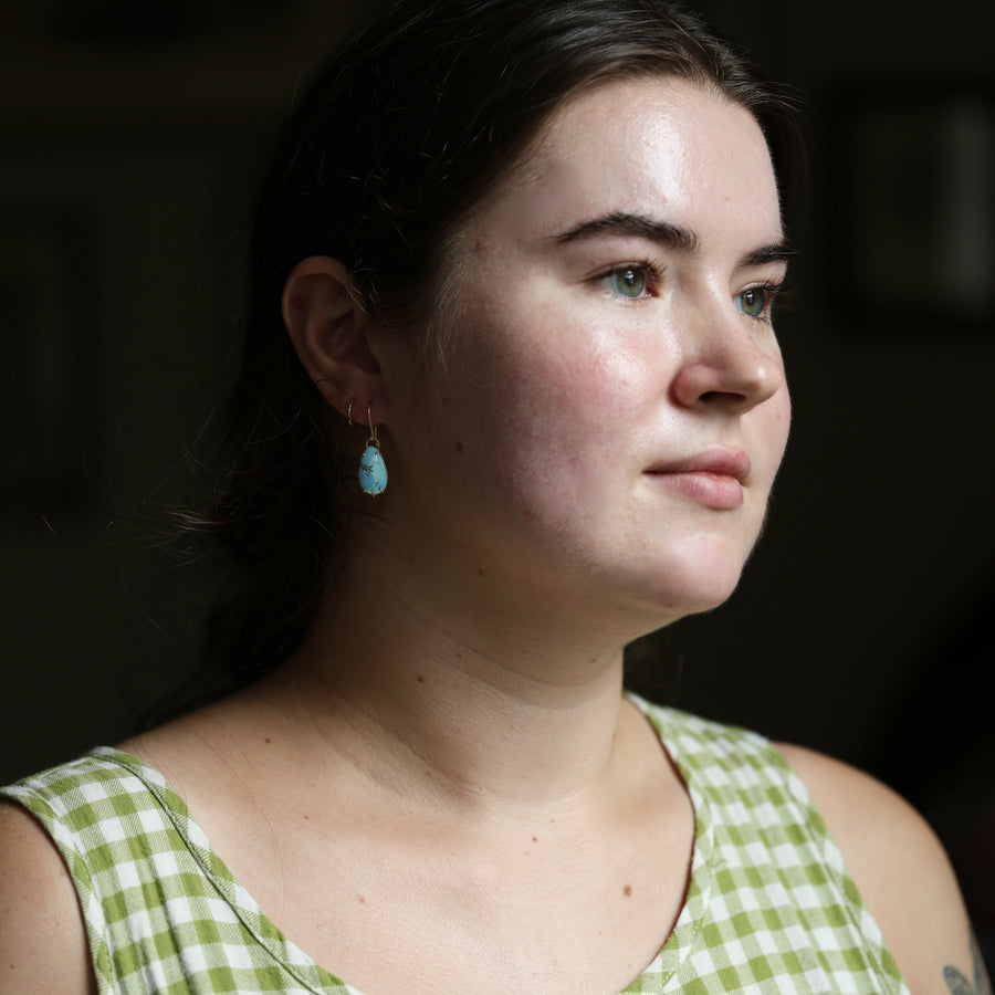 Woman wearing a green checkered dress with a blurred dark background
