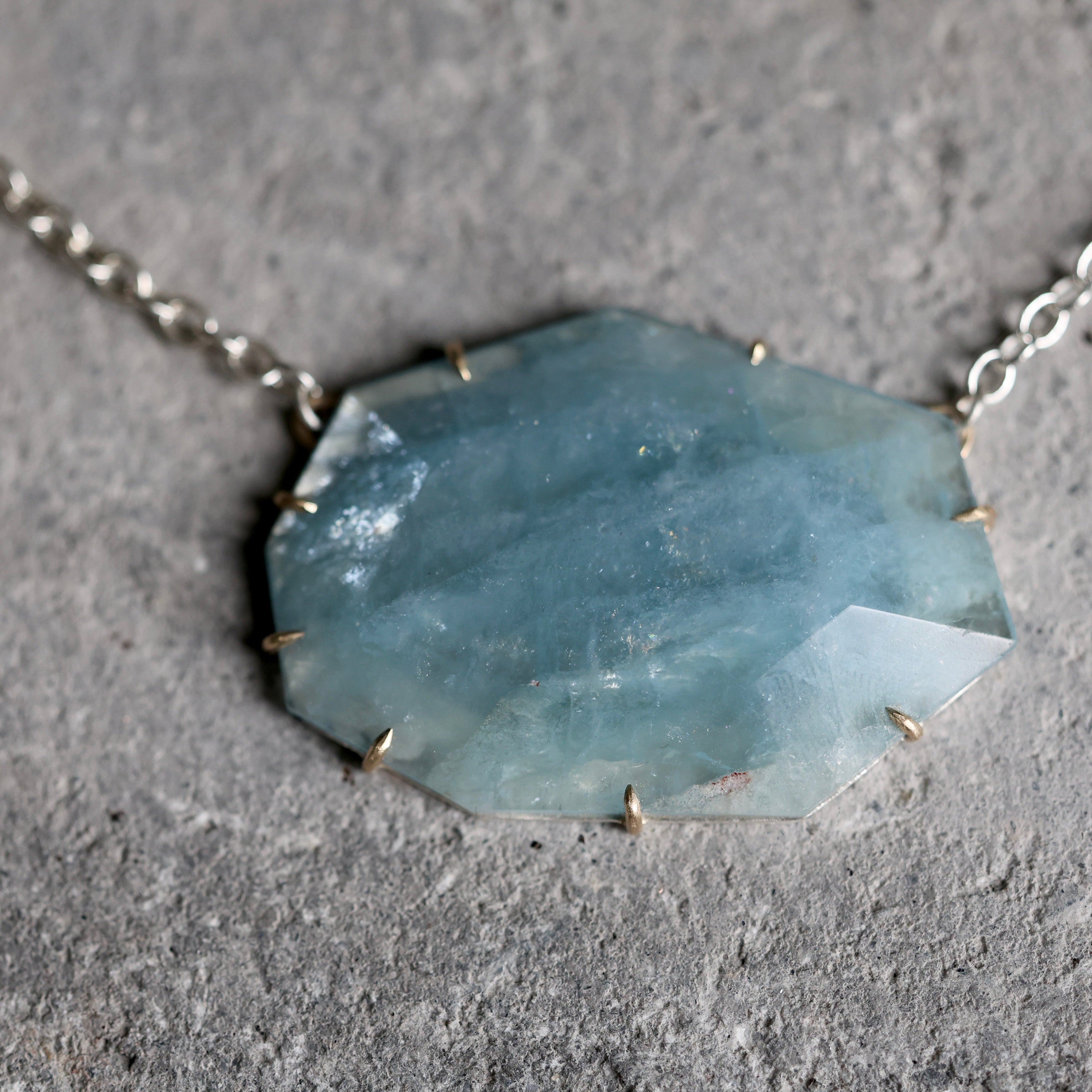 Necklace with a large, faceted blue stone pendant on a gray surface