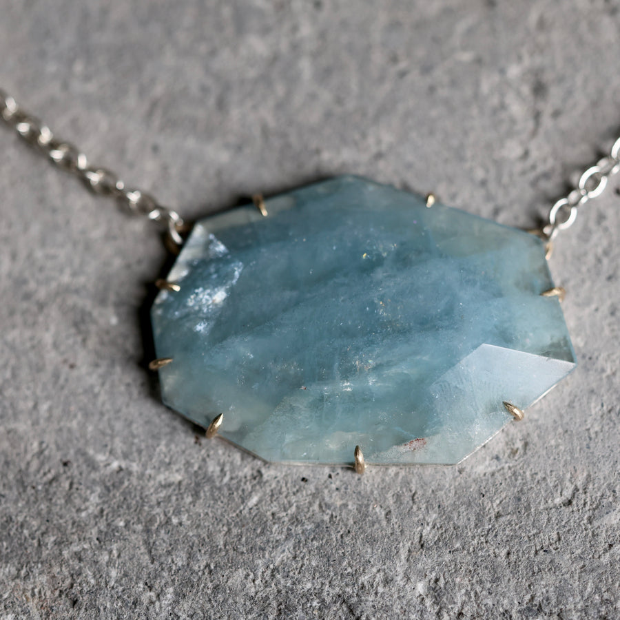 Necklace with a large, faceted blue stone pendant on a gray surface