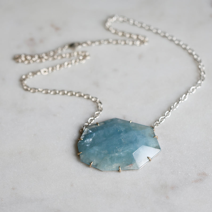 Necklace with a blue pendant on a marble surface