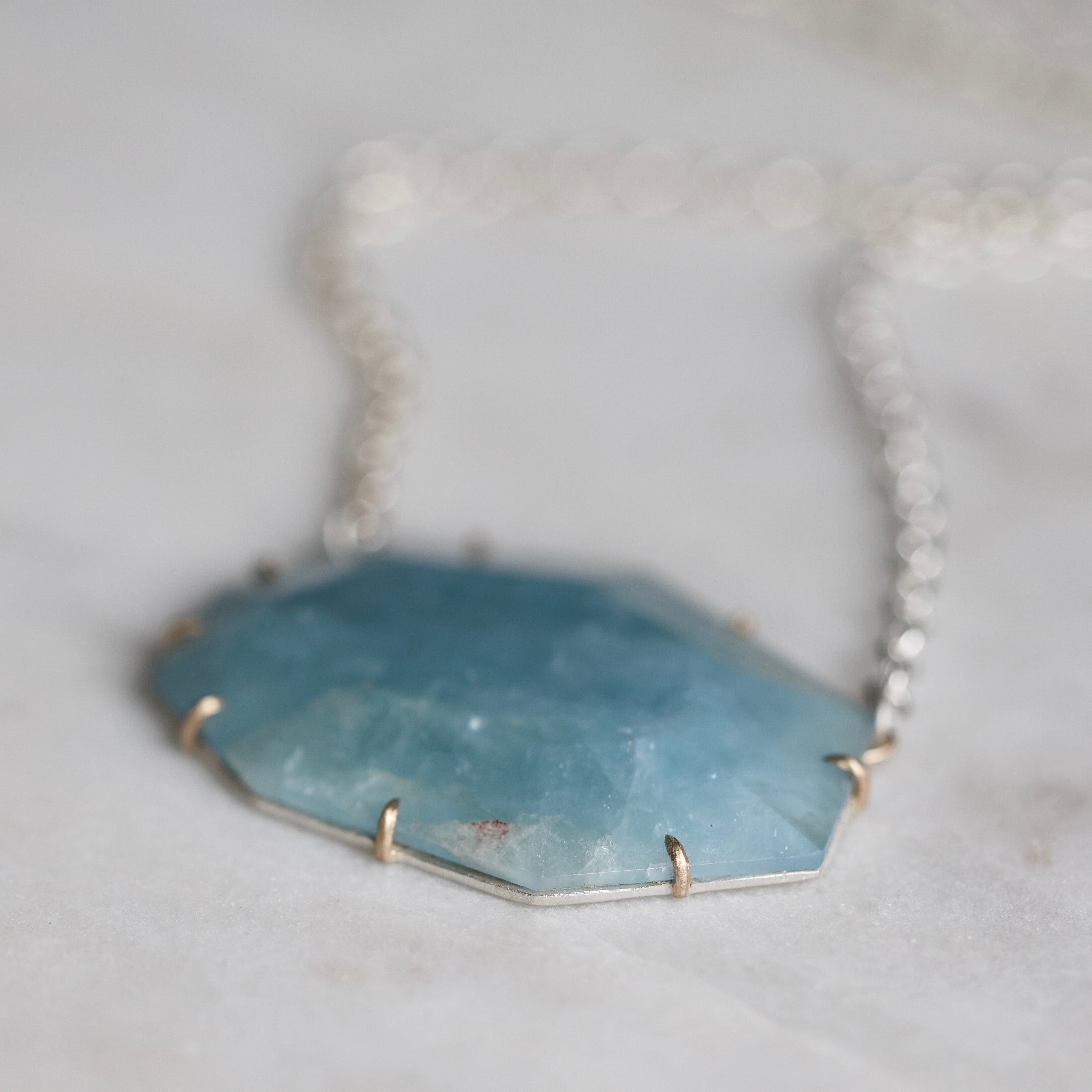 Necklace with a blue stone pendant on a light gray background