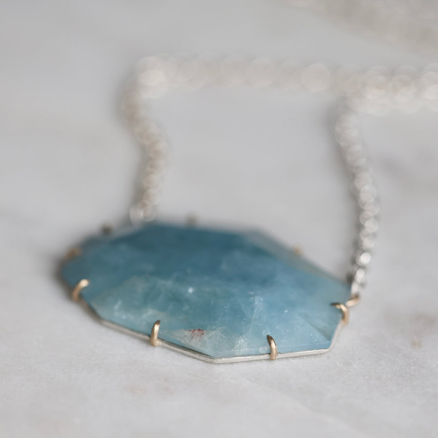 Necklace with a blue stone pendant on a light gray background
