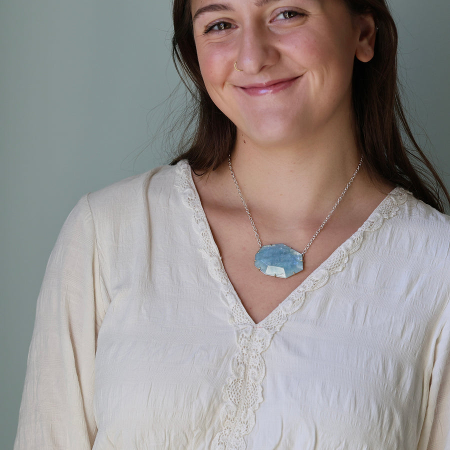 Woman wearing a white blouse and necklace with a gray background