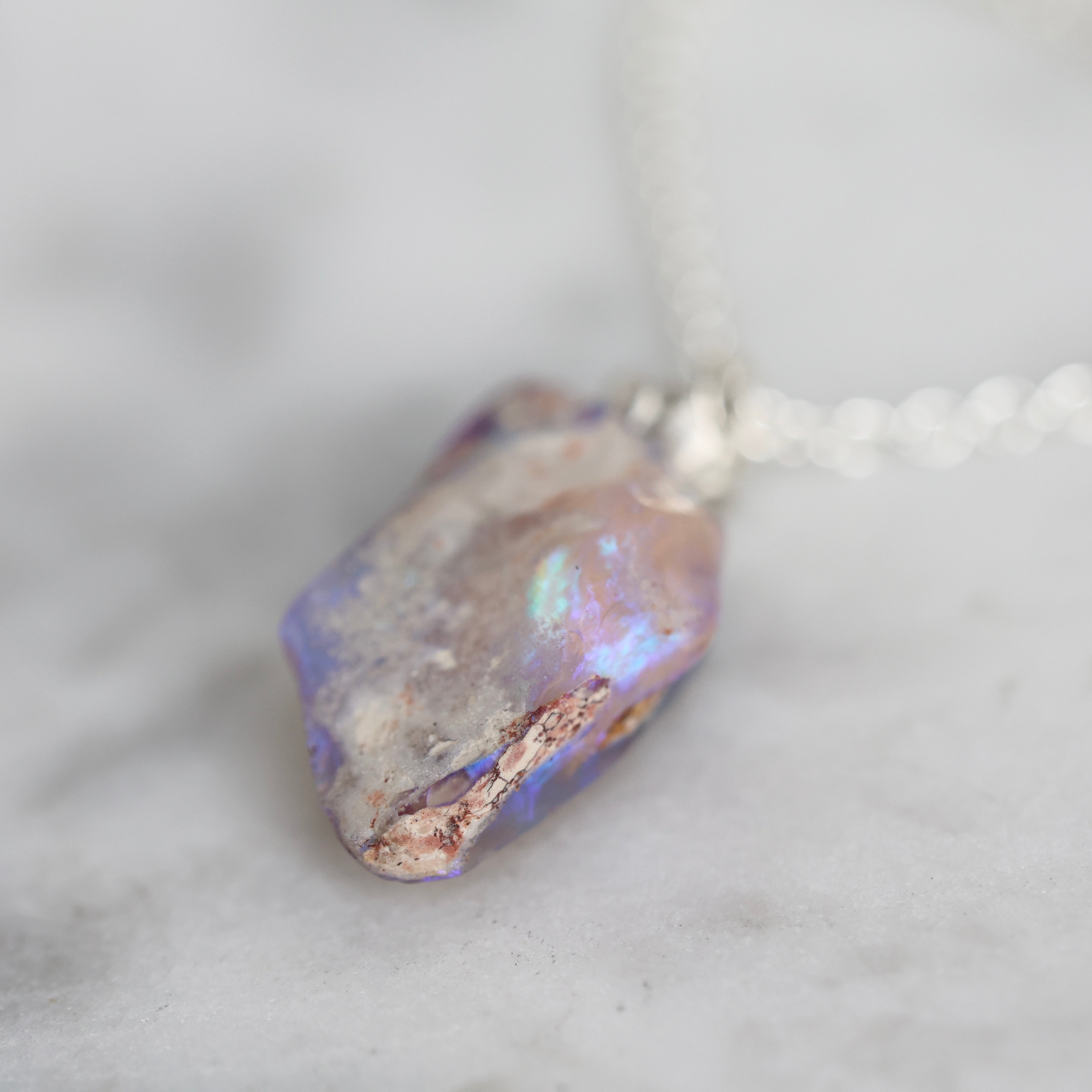 detail of 6.35ct opalized wood fossil pendant with a bright sterling silver rose accent and chain.