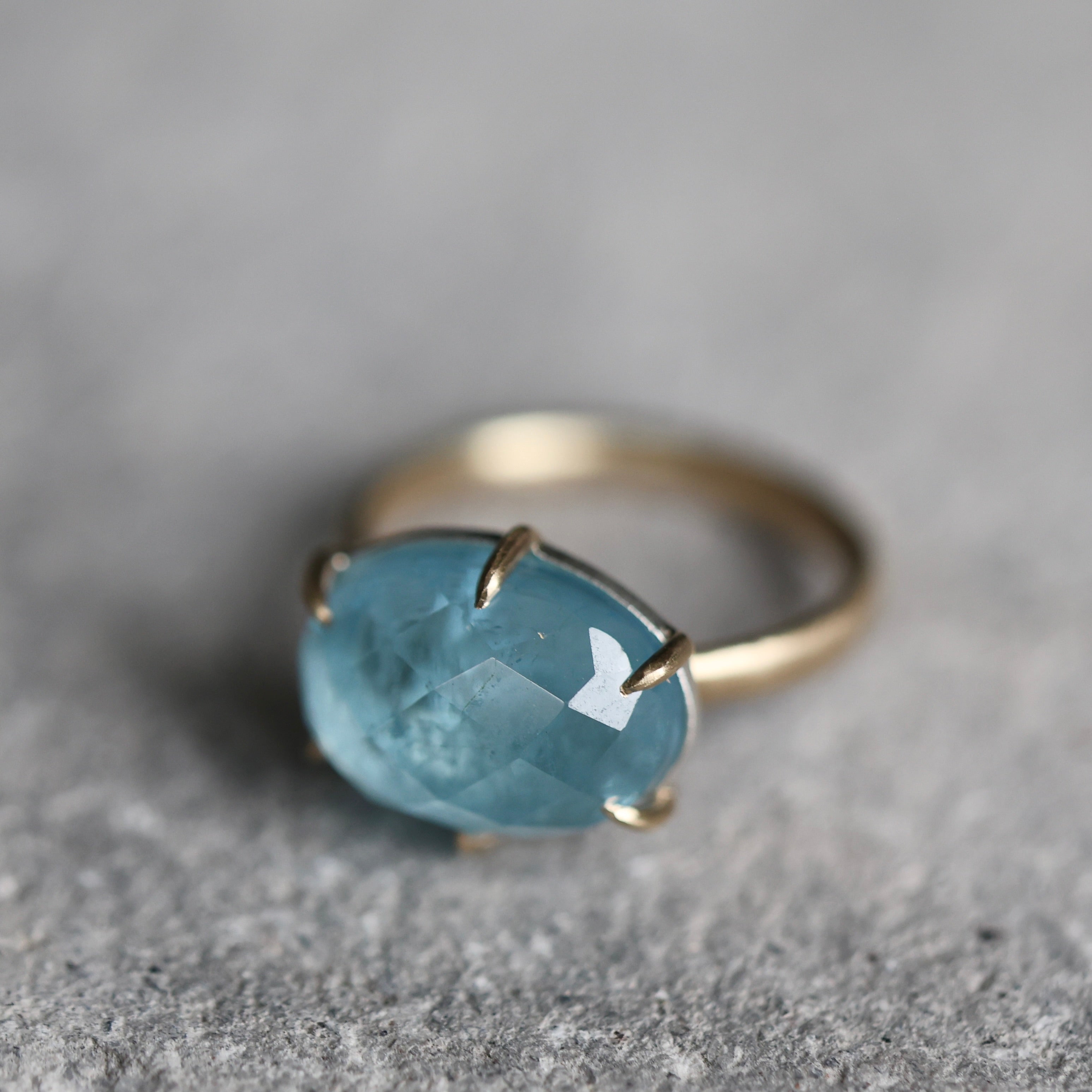 Gold ring with a blue gemstone on a gray surface
