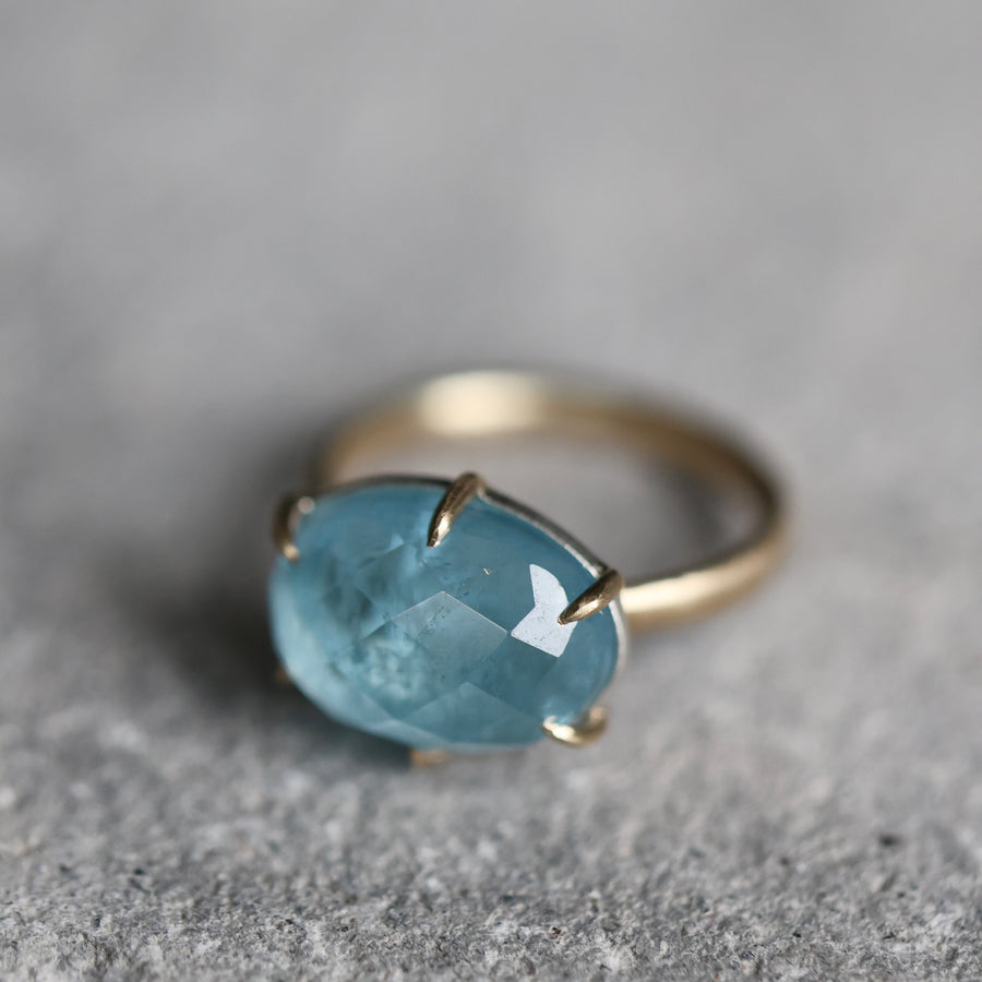 Gold ring with a blue gemstone on a gray surface