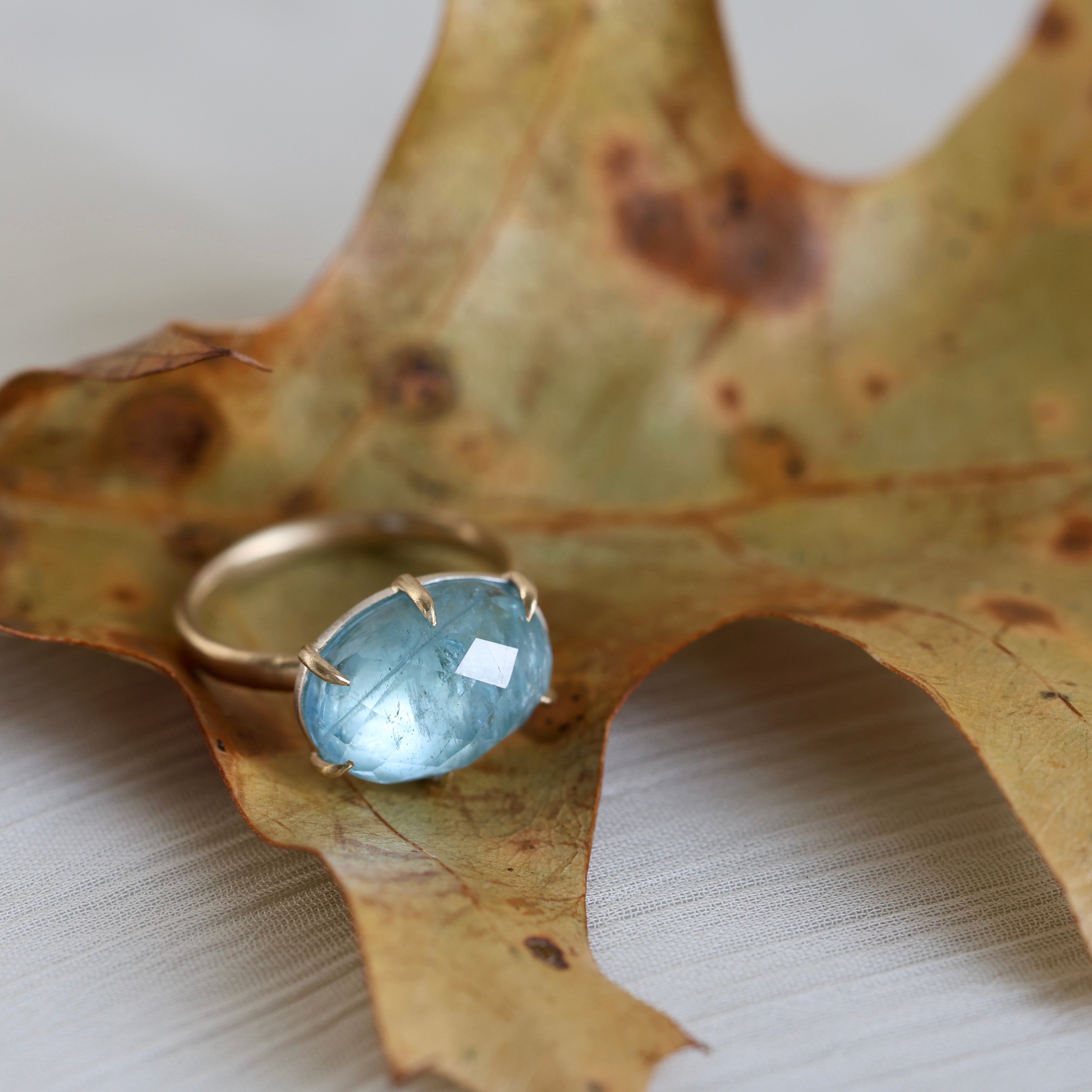 Gold ring with a blue gemstone on a textured surface