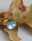 Gold ring with a blue gemstone on a textured surface