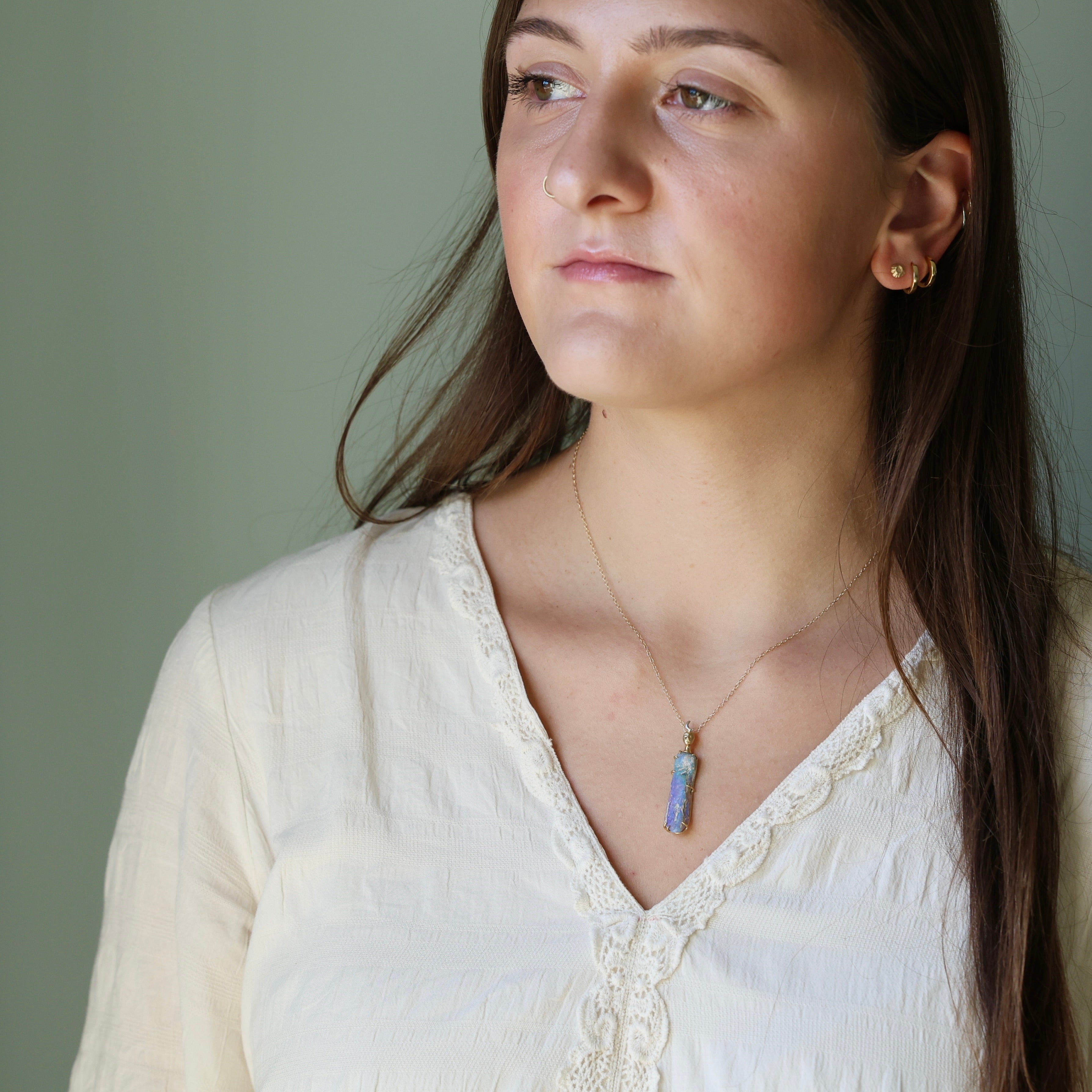 Woman wearing a necklace with a pendant against a neutral background