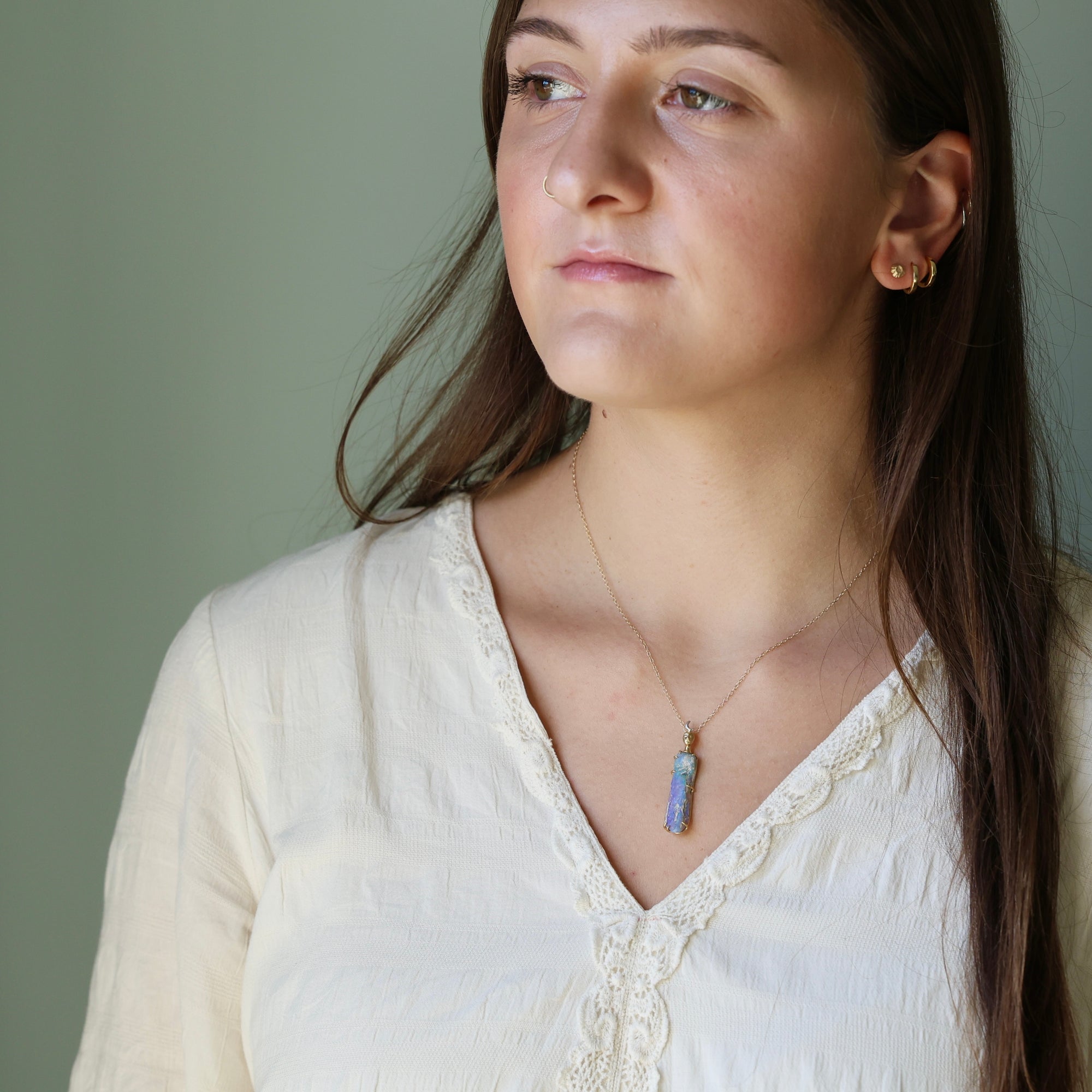 Woman wearing a necklace with a pendant against a neutral background