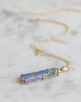 Necklace with a colorful opal and gold face with crescent moon on a marble surface