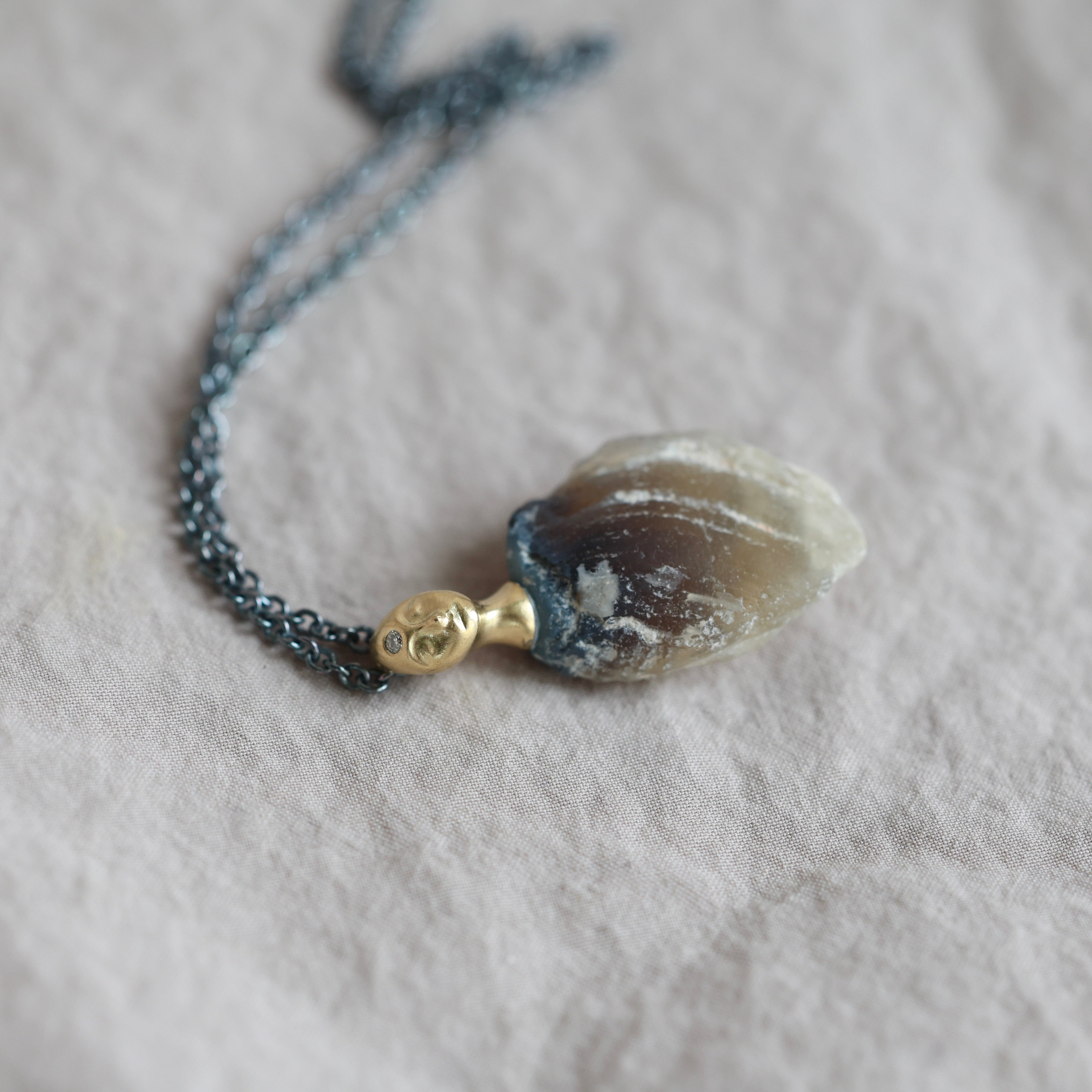 Necklace with a clambshell fossil pendant on a textured fabric background