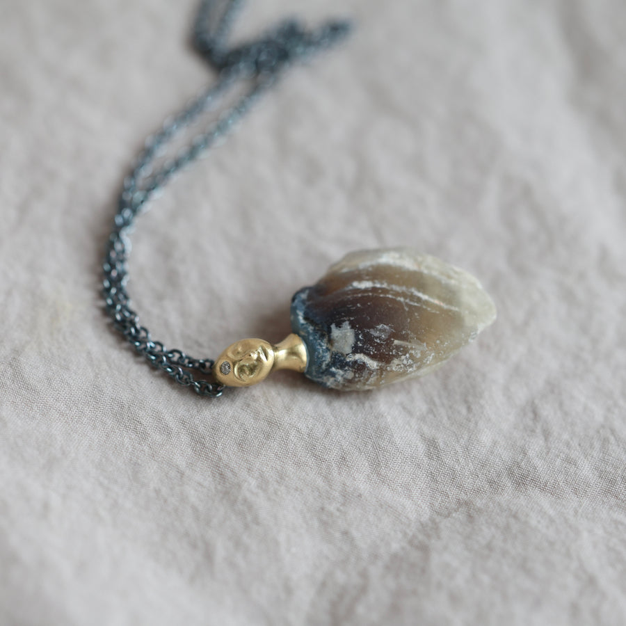 Necklace with a clambshell fossil pendant on a textured fabric background