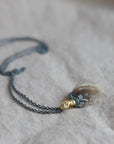 Necklace with a clambshell fossil pendant on a textured fabric background