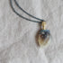 Necklace with a clambshell fossil pendant on a textured fabric background