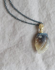 Necklace with a clambshell fossil pendant on a textured fabric background