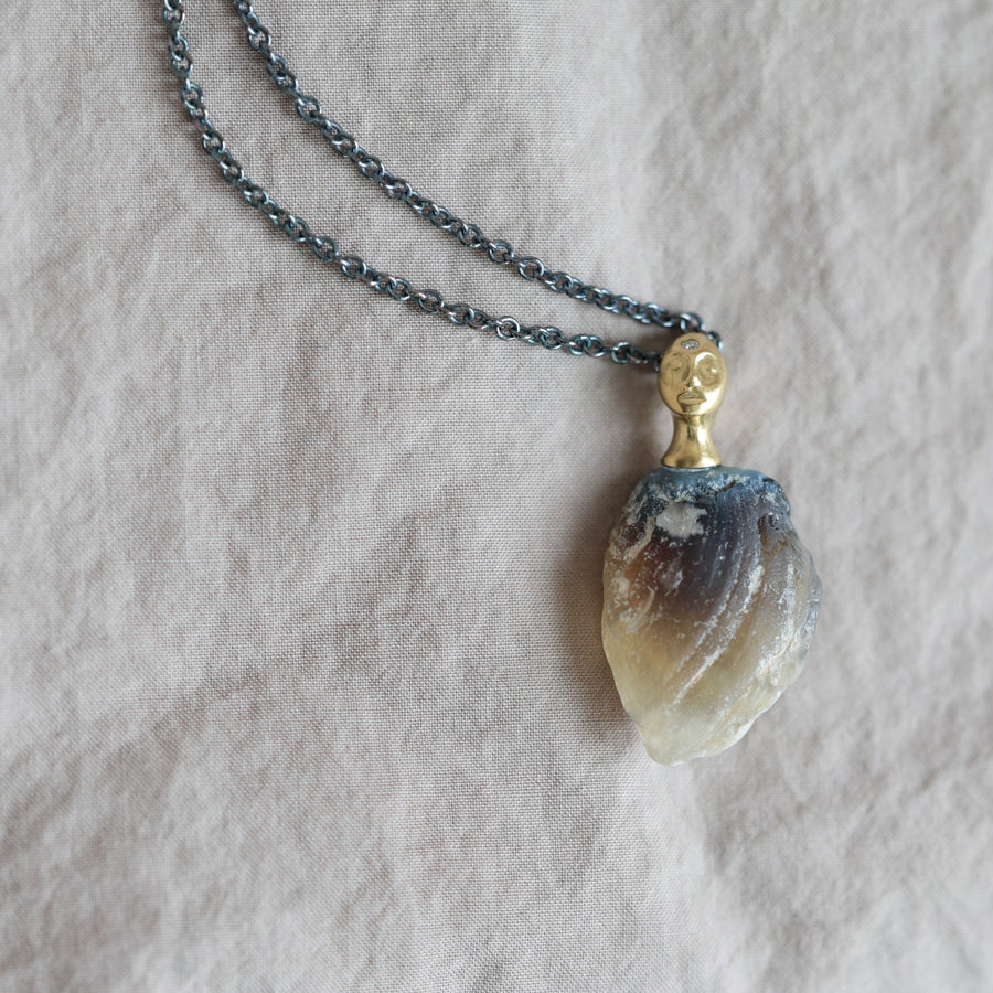 Necklace with a clambshell fossil pendant on a textured fabric background