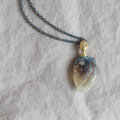 Necklace with a clambshell fossil pendant on a textured fabric background