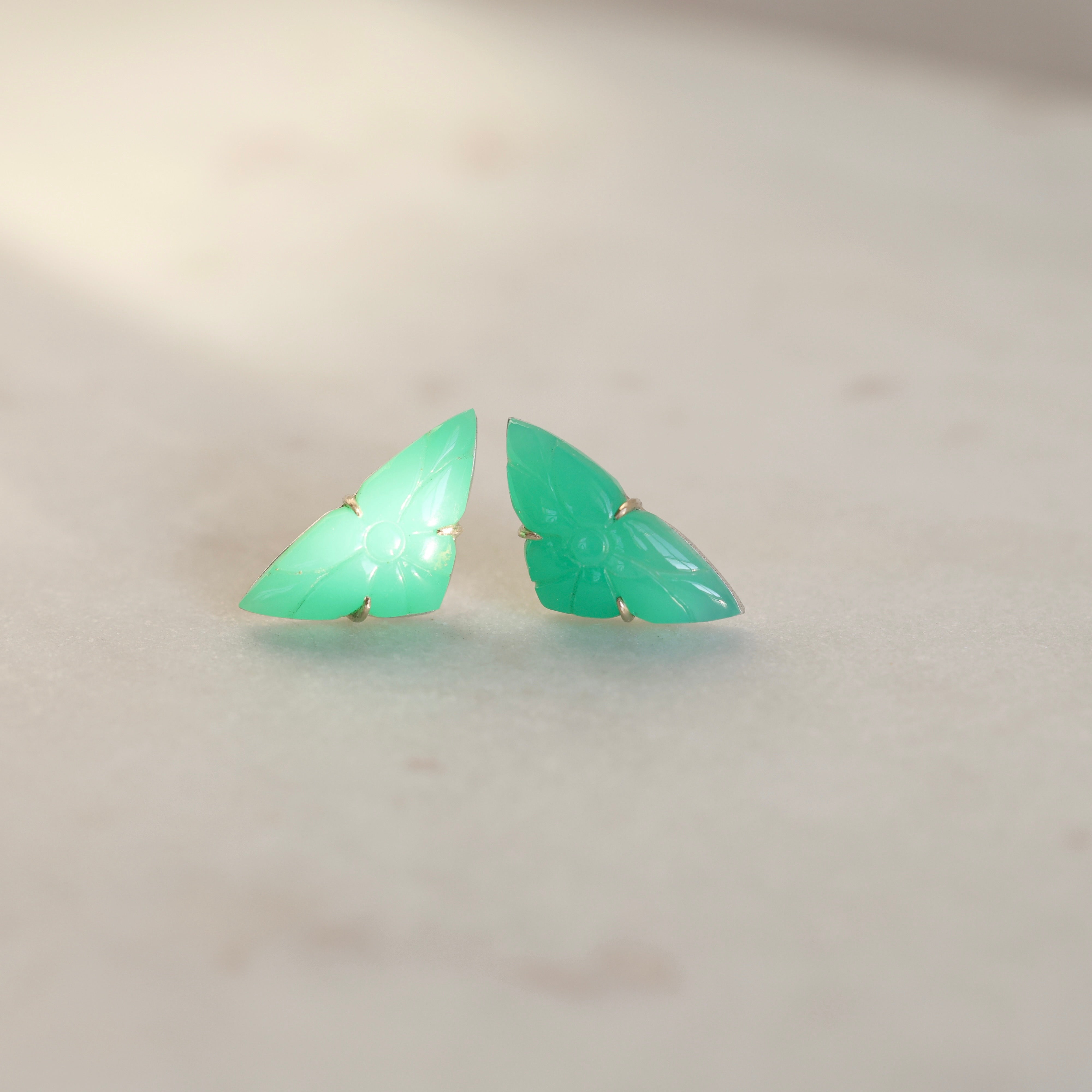 Pair of green butterfly-shaped earrings on a light gray background