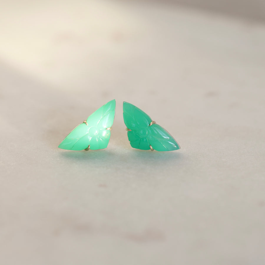 Pair of green butterfly-shaped earrings on a light gray background