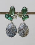 Pair of earrings with green gemstones and textured silver drops on a gray background