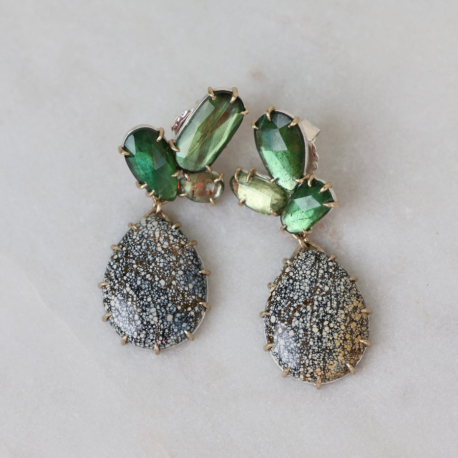 Pair of earrings with green and gray stones on a light background