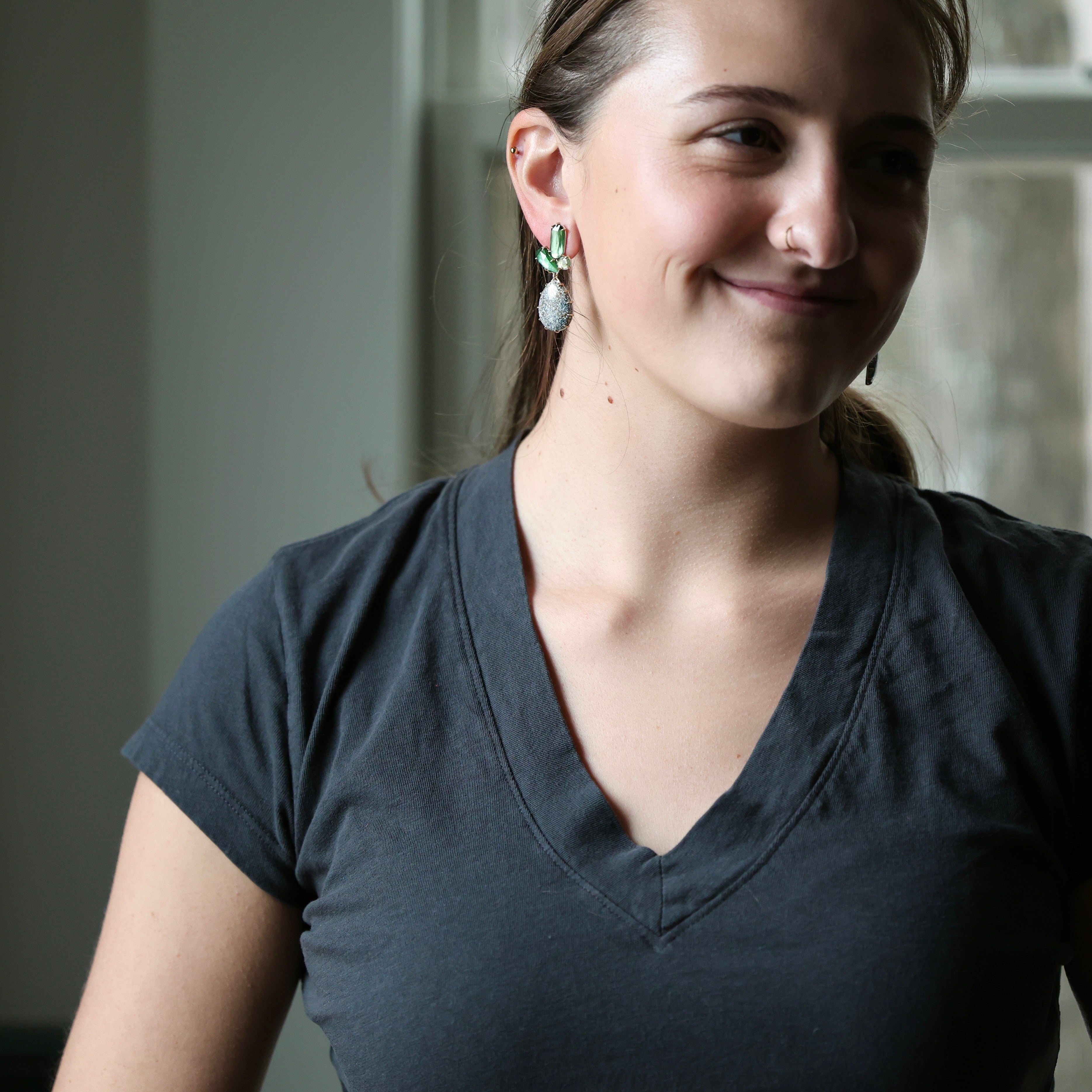 woman wearing dark grey shirt with green earrings