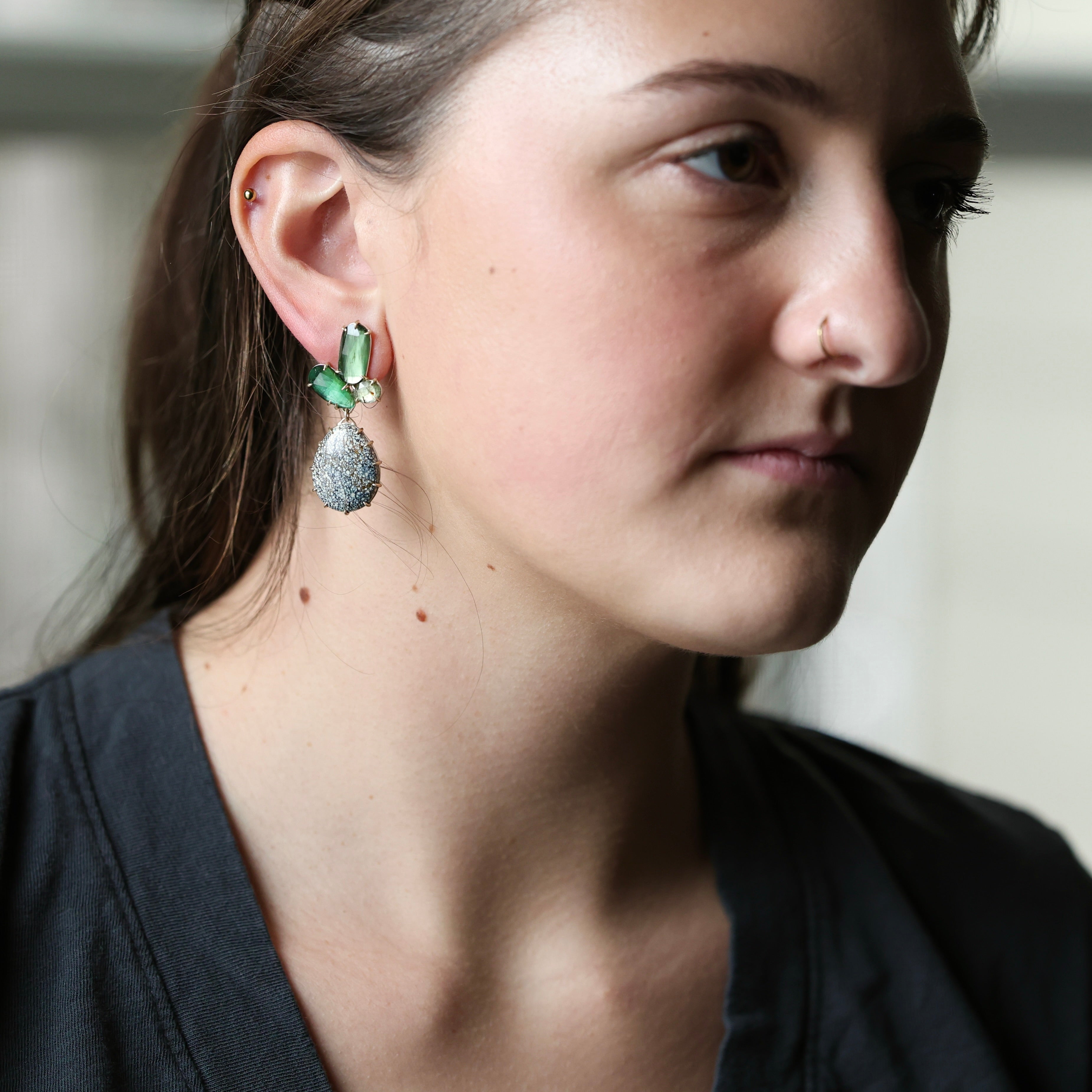 woman wearing dark grey shirt with green earrings