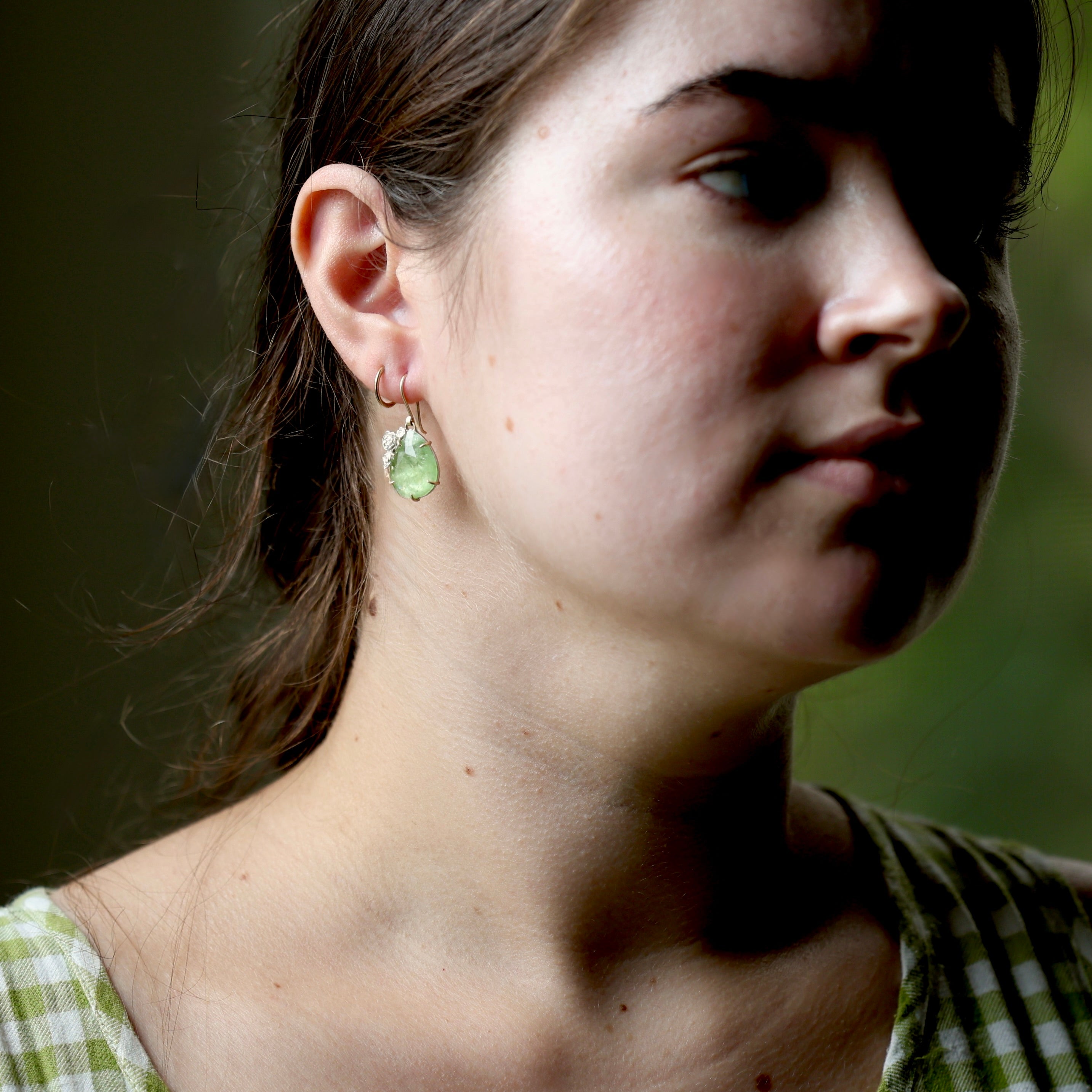 Close-up of a woman wearing green earrings with a blurred background