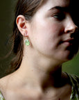 Close-up of a woman wearing green earrings with a blurred background