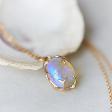 Oval opal with purple and green colors grasped in gold branches with diamonds berries, pendant on gold chain by hannah blount
