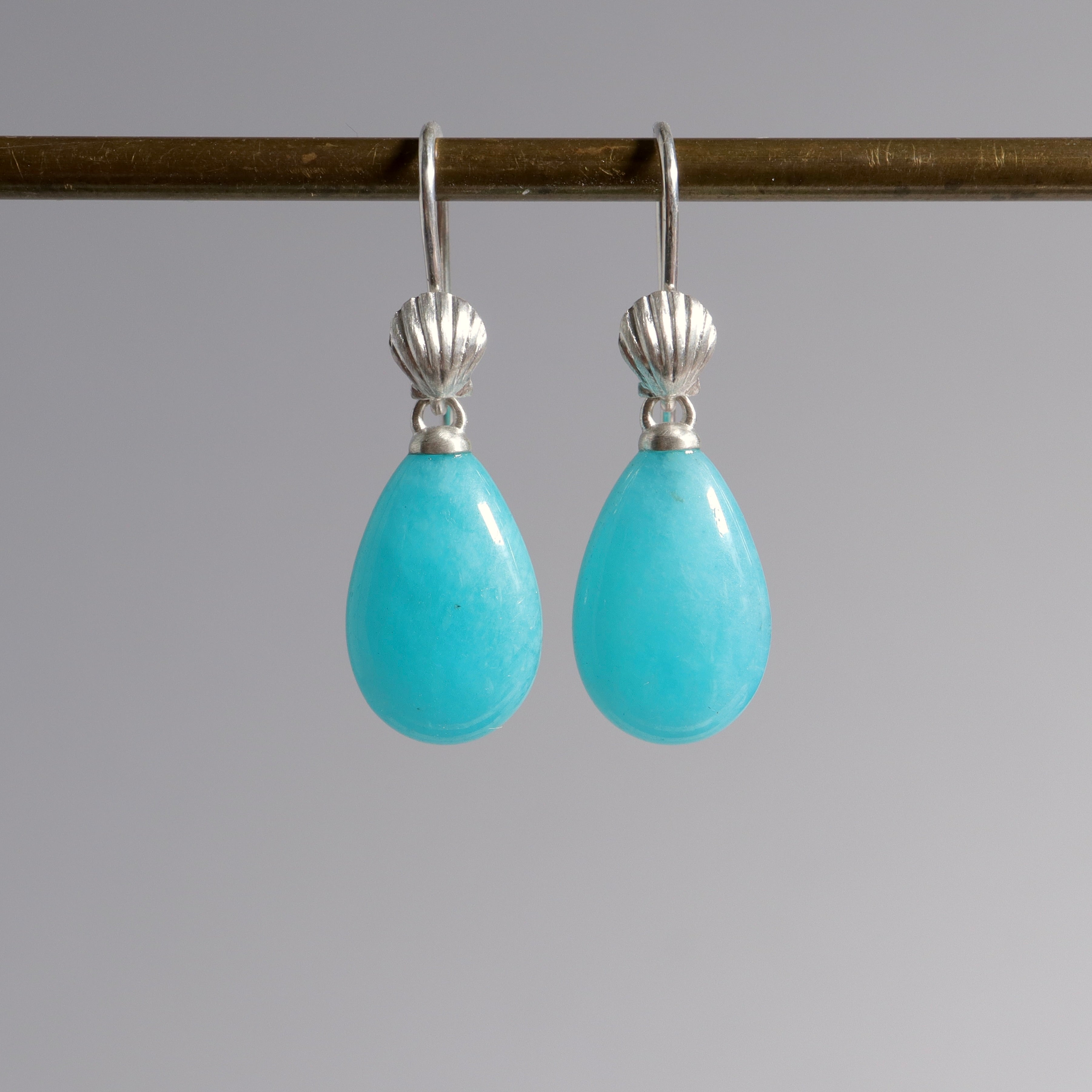 teardrops of bright teal blue amazonite hang beneath silver ear wires featuring little scallop shells in silver