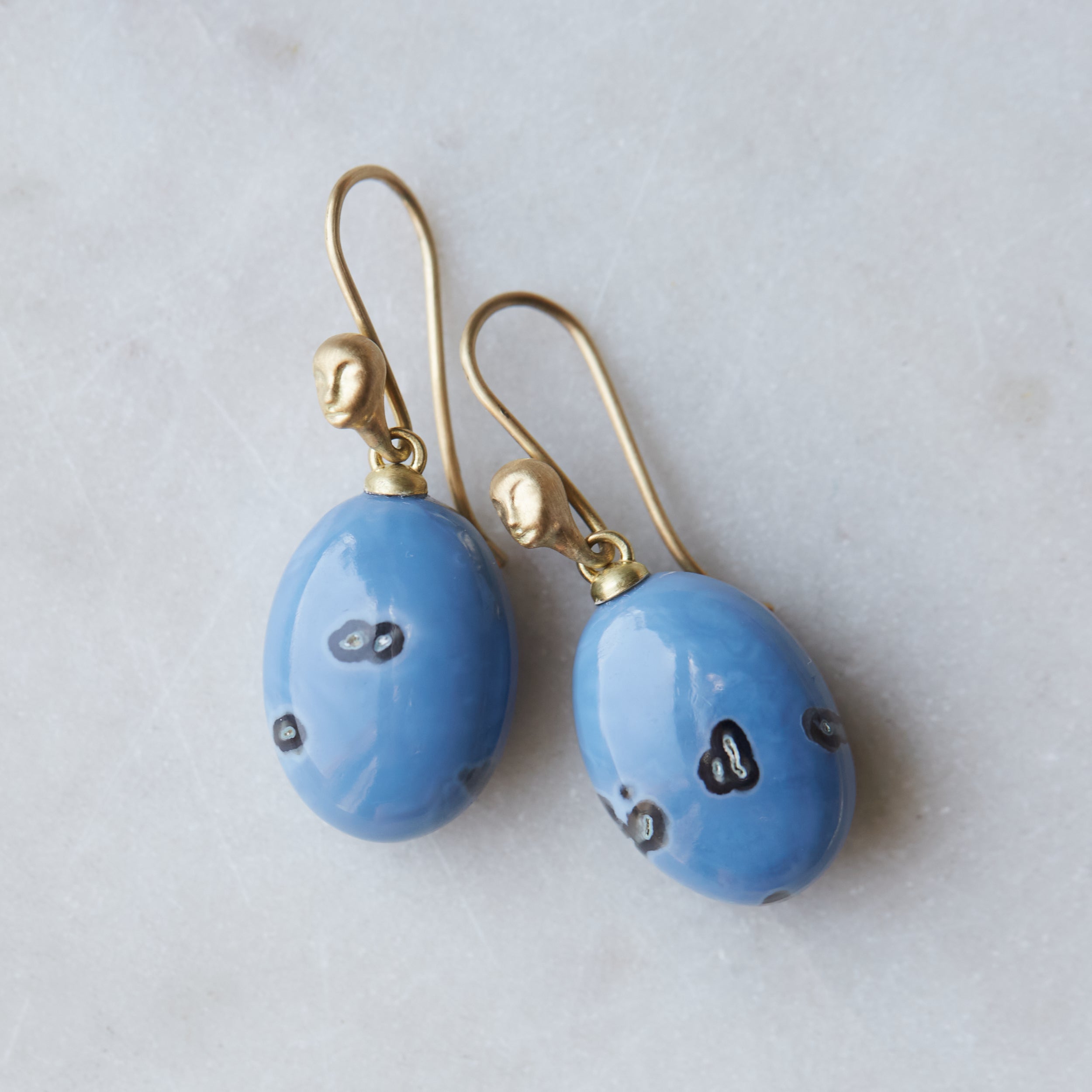 mottled blue common opal oval drops set as earrings with ear wires featuring gold Lady faces
