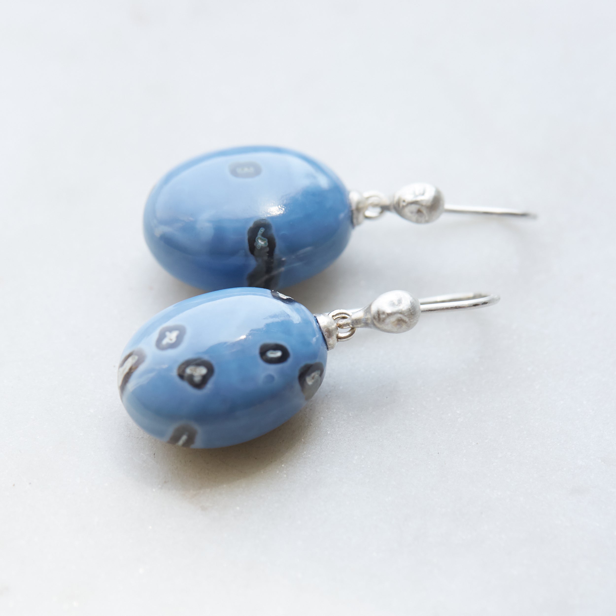periwinkle blue common opal with mottled black spots. Little Lady faces adorn the silver ear wires.