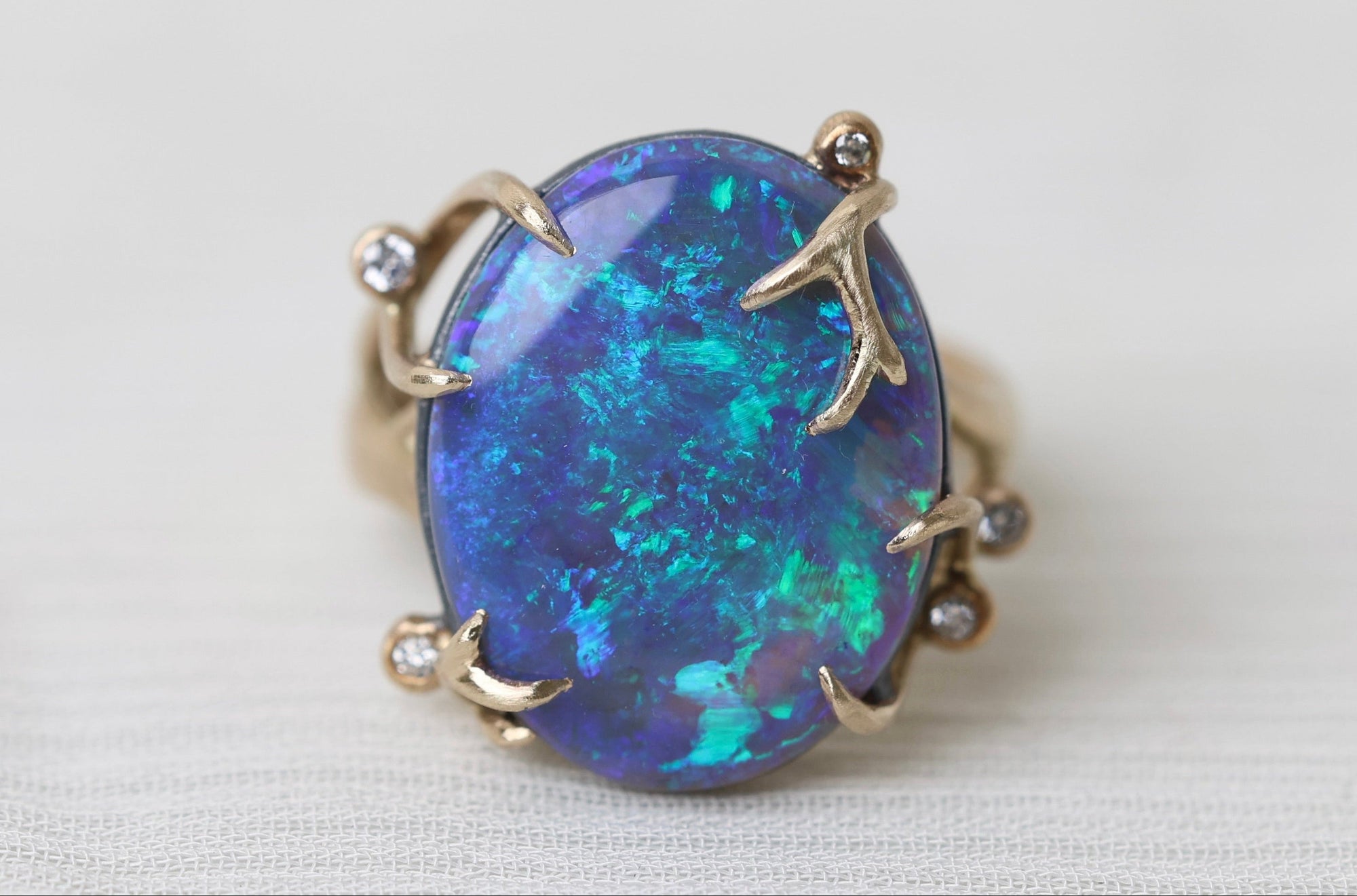 Ring with a blue opal stone on a white fabric background