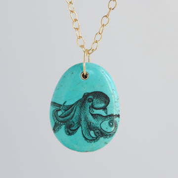 Turquoise pendant with octopus design on a gold chain against a light gray background