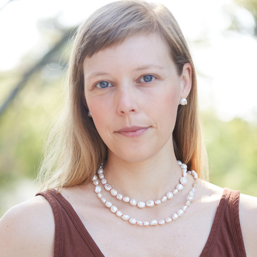 Baroque white freshwater pearl necklace with coral-hued silk and gold clasp by Hannah Blount