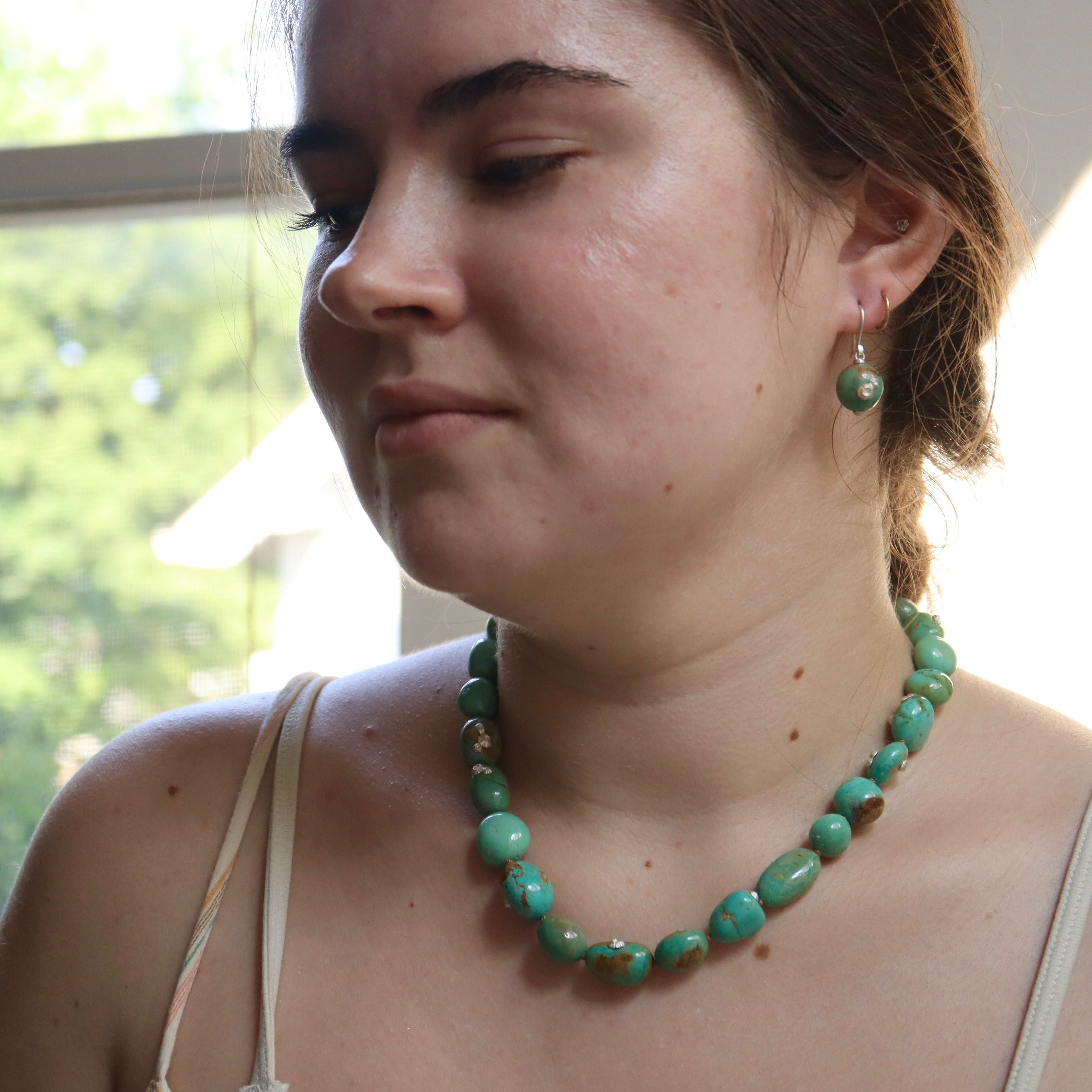 turquoise strand shown on person with turquoise earrings